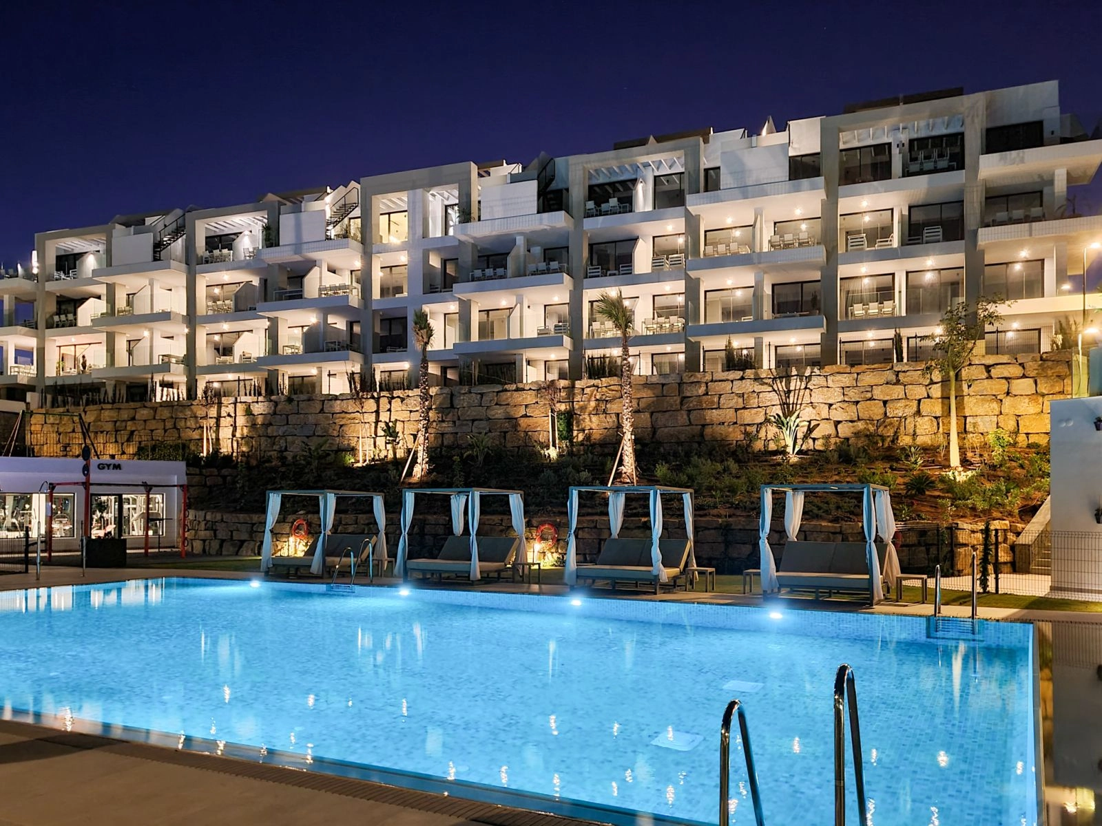 Het appartementencomplex is 's avonds prachtig verlicht, wat een elegante en veilige sfeer creëert.