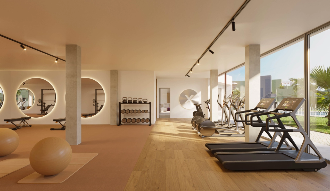 Een volledig uitgeruste fitnessruimte met grote ramen die uitkijken op de tuinen en het zwembad.