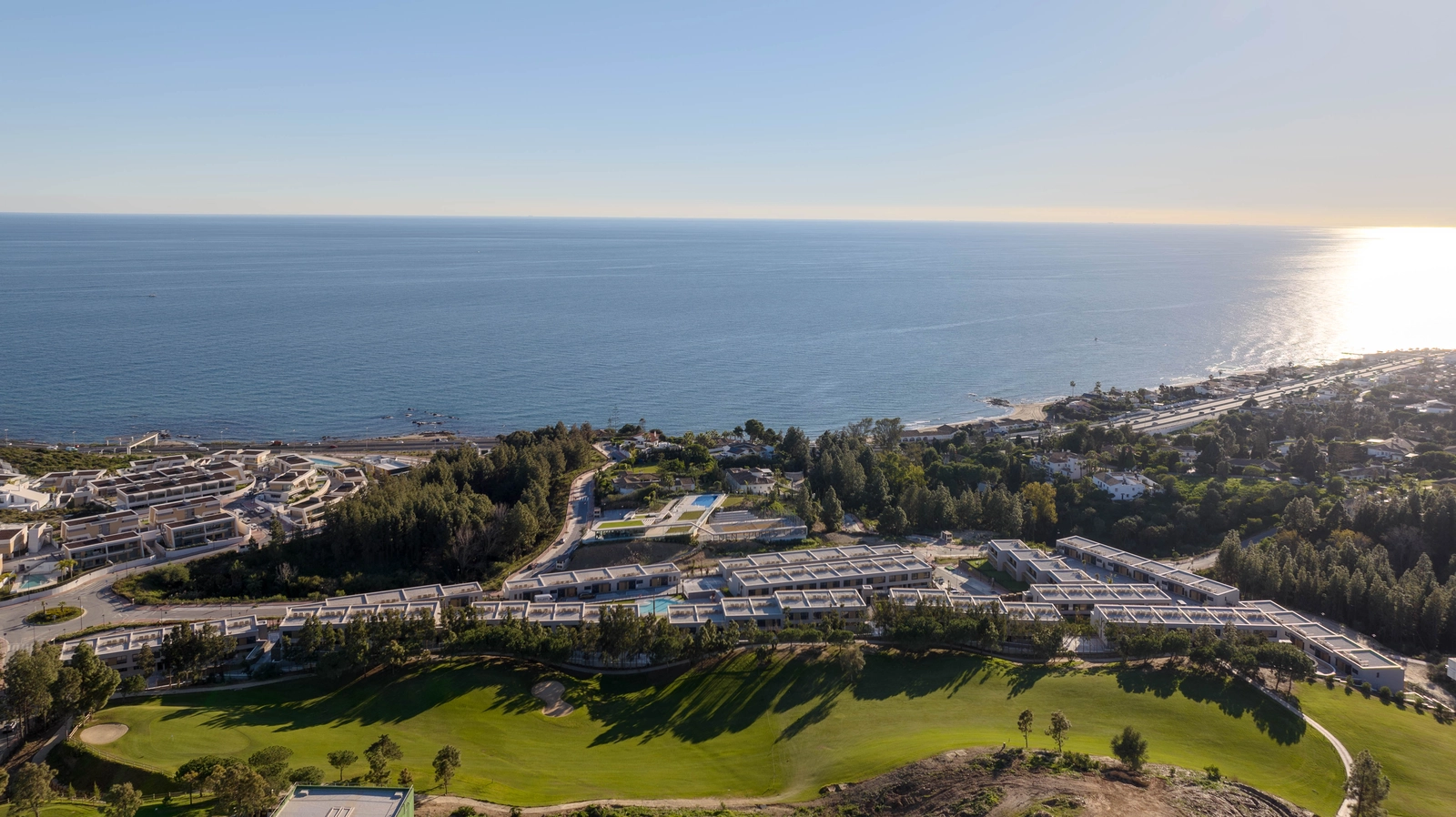 Een luchtfoto van Evergreen Homes, perfect gelegen tussen de groene fairways van de golfbaan en de blauwe Middellandse Zee.