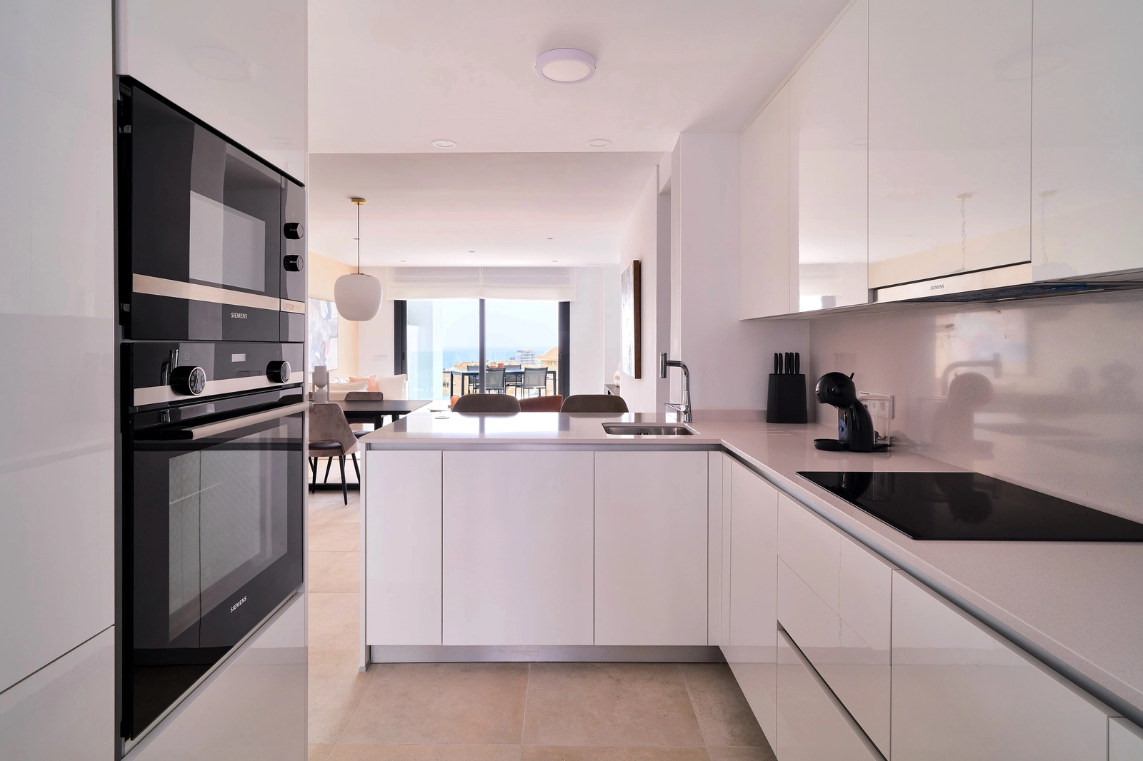 Een moderne, volledig uitgeruste keuken met ontbijtbar, ontworpen voor zowel functionaliteit als stijl, die overloopt in de woonkamer.