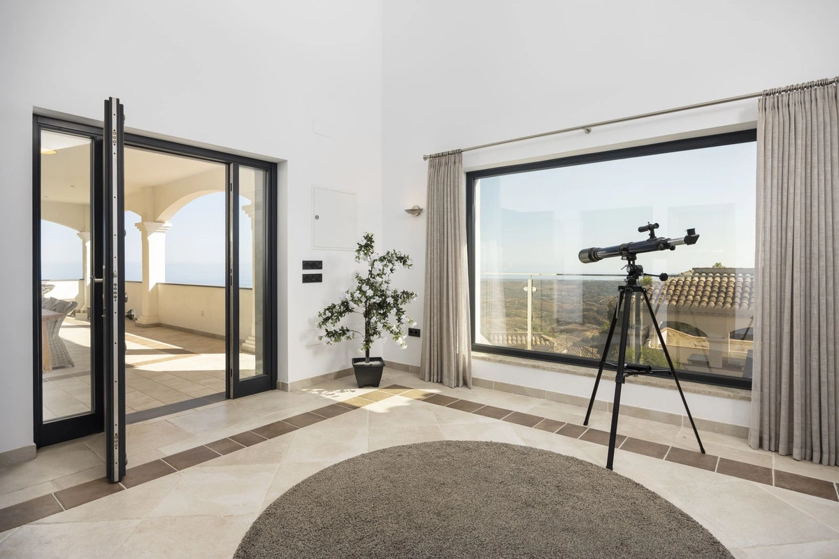 Een rustige hoek van het huis waar grote ramen het spectaculaire landschap omlijsten en deuren toegang geven tot het terras.