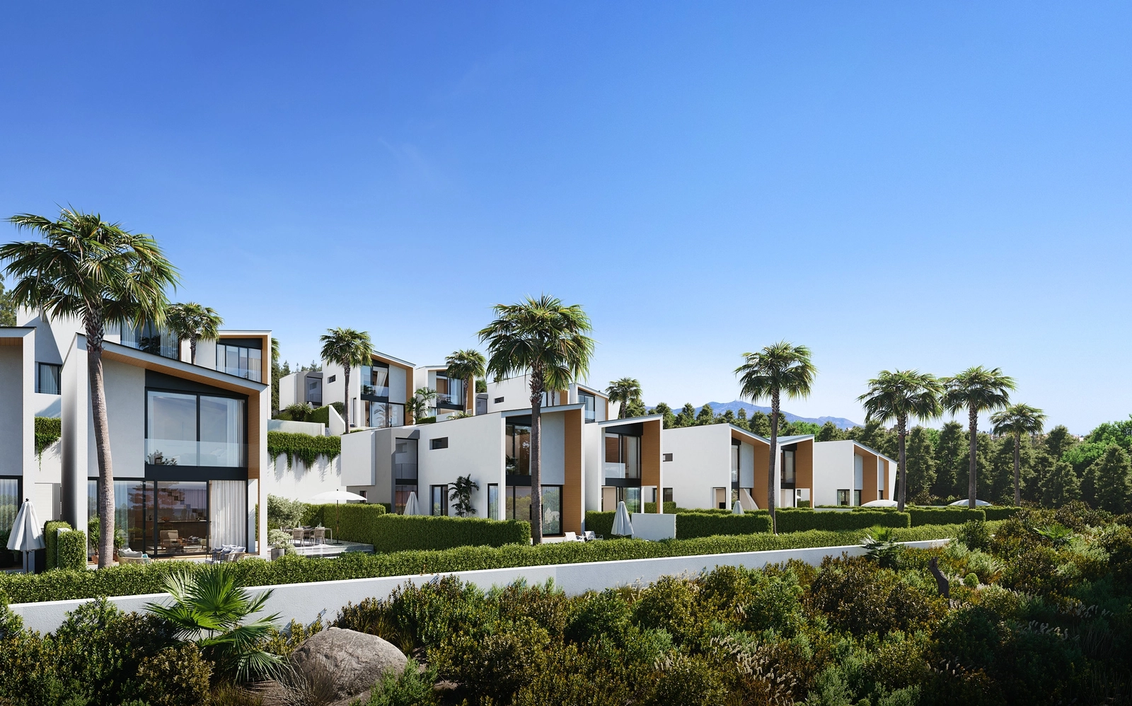 De opvallende moderne architectuur van de villa's steekt af tegen de helderblauwe lucht en de weelderige groene omgeving.