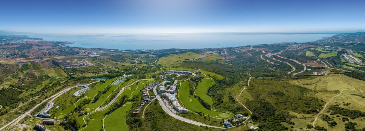 Een uitgebreid luchtbeeld van het Sunny Golf project, perfect geïntegreerd met de weelderige groene fairways van Estepona Golf en de sprankelende Middellandse Zee daarachter.